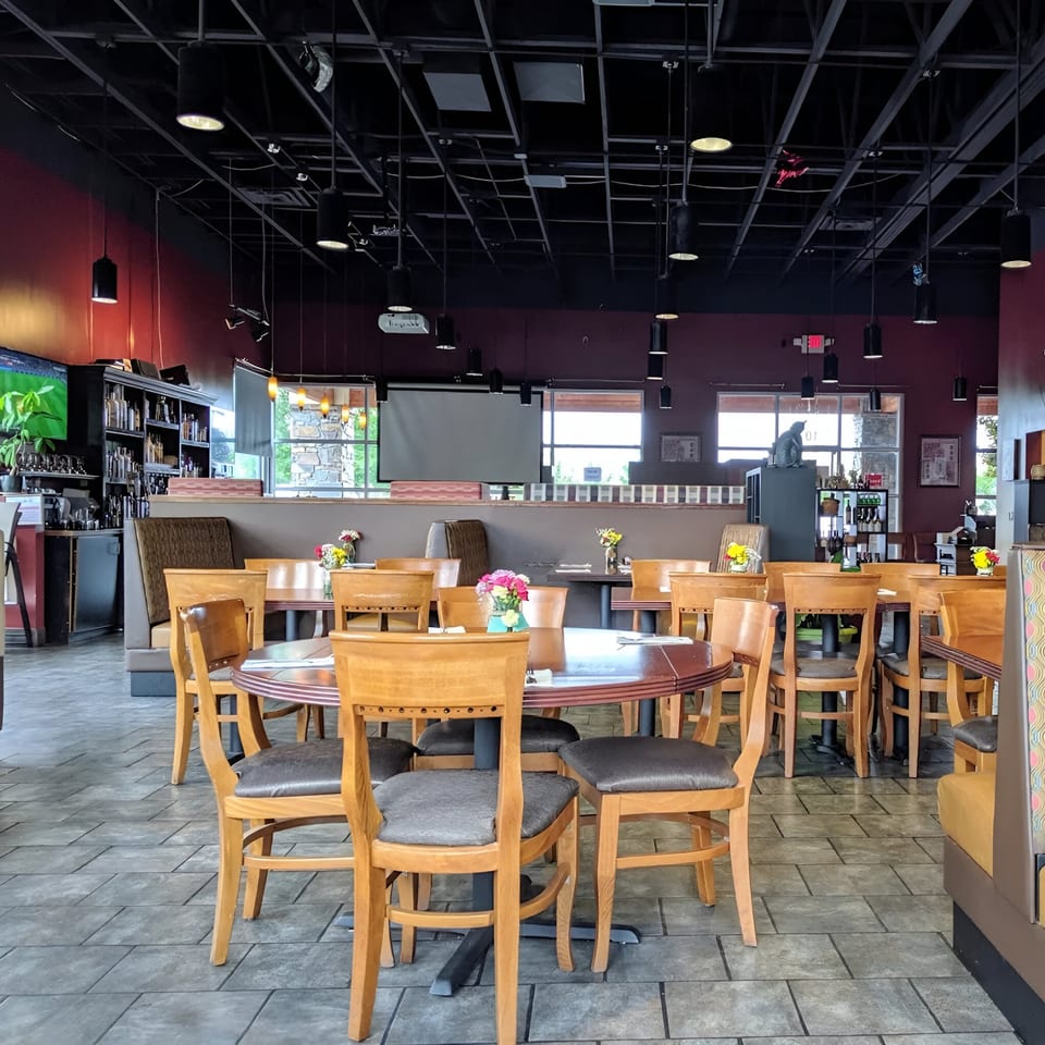 Interior of Wild Tiger Thai restaurant with wooden tables and chairs, red walls, and a dark ceiling.