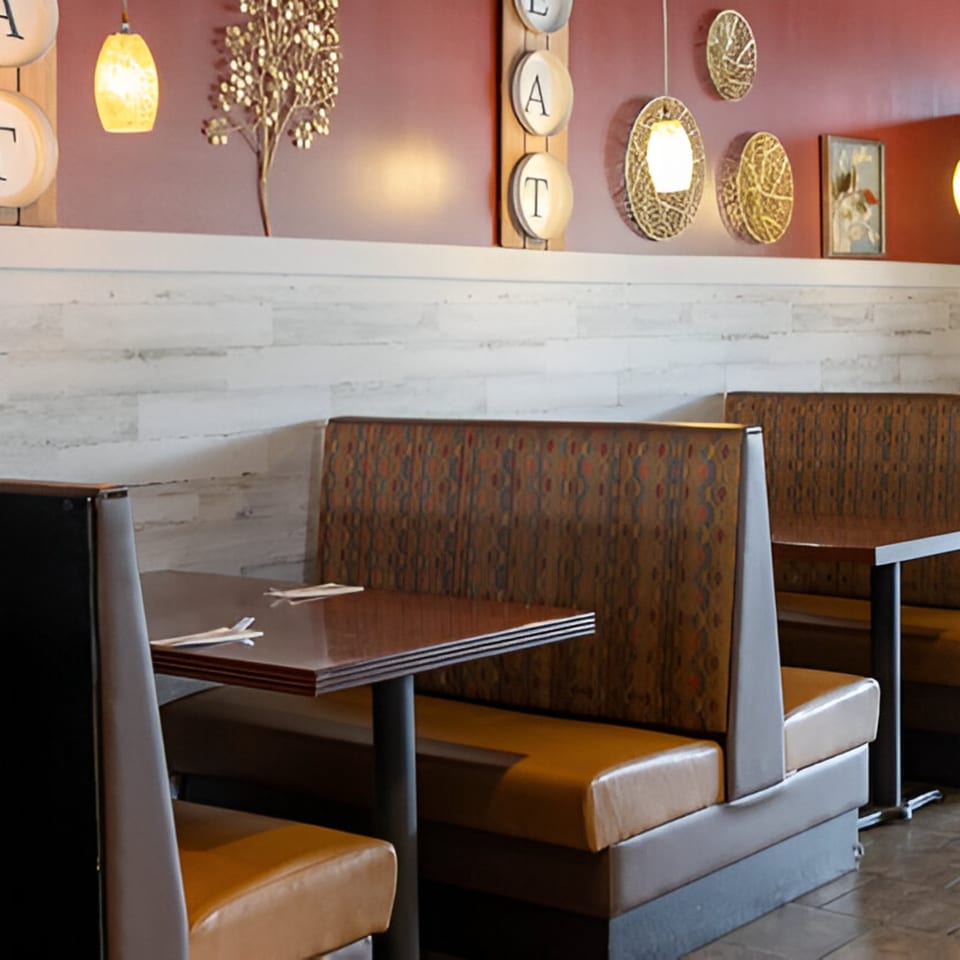 Cozy Wild Tiger Thai dining area with brown booths, dark tables, and decorative wall art.
