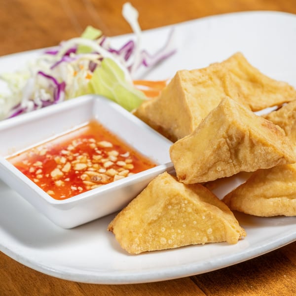 Crispy fried tofu triangles with a side of sweet chili dipping sauce and shredded cabbage salad.