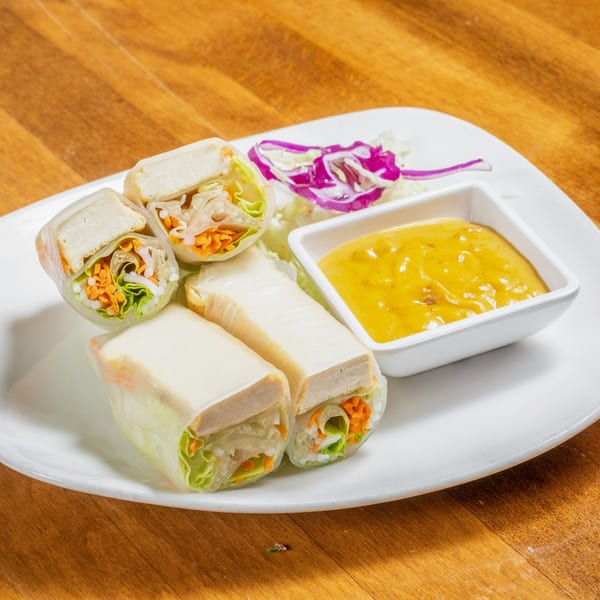 Fresh Thai spring rolls with tofu, lettuce, and carrots, served with a side of peanut sauce.