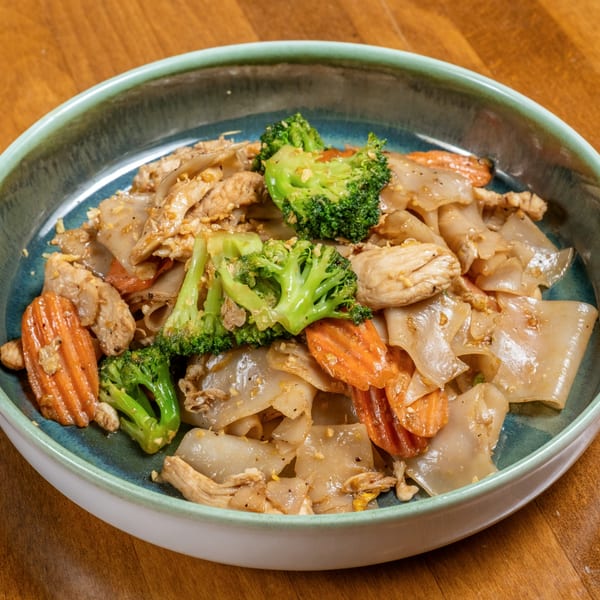 Wild Tiger Thai's Pad See Ew with wide noodles, chicken, broccoli, and carrots in a teal bowl.