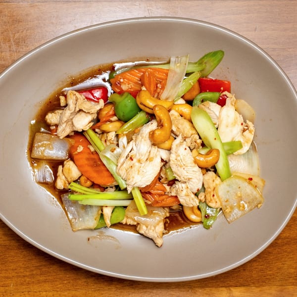 Wild Tiger Thai's cashew chicken stir-fry with vegetables and a savory sauce on a gray plate.
