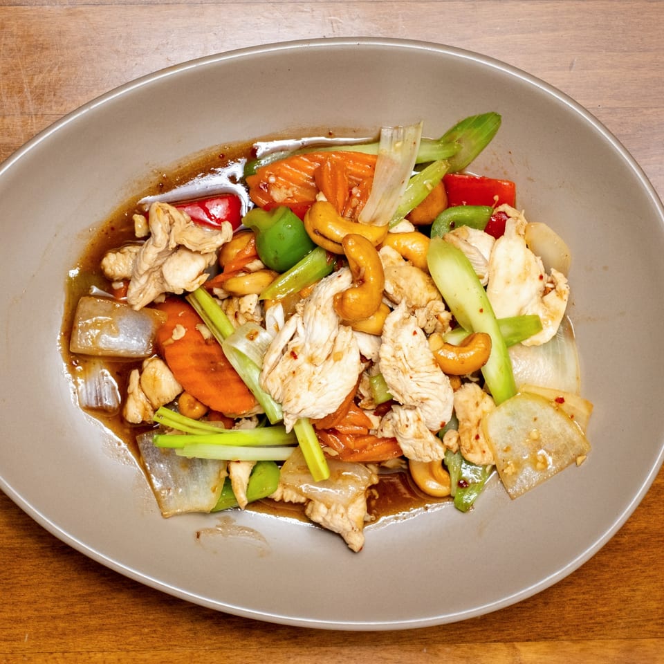 Wild Tiger Thai's cashew chicken stir-fry with vegetables and a savory sauce on a gray plate.